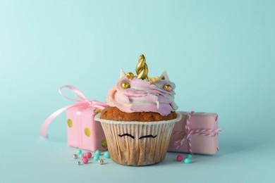 Photo of Cute sweet unicorn cupcake and gift boxes on light turquoise background
