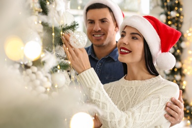 Happy couple decorating Christmas tree at home