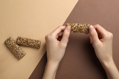 Photo of Woman holding kozinaki bar on color background, top view