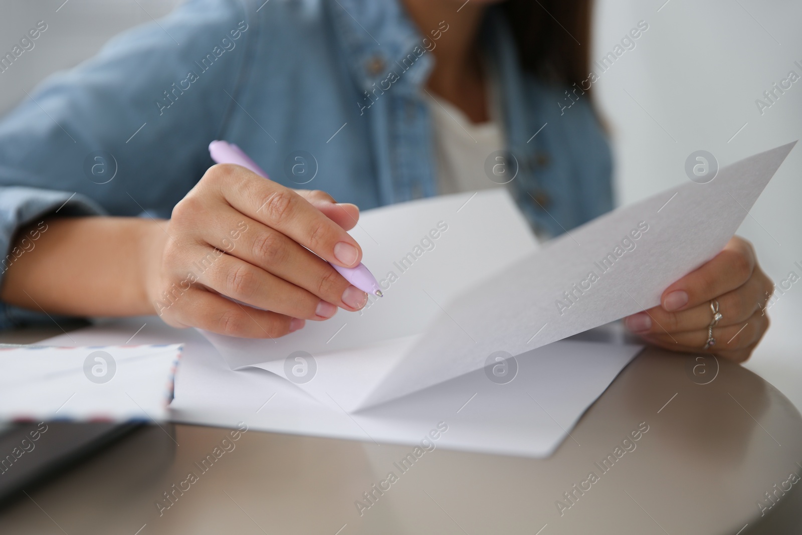Photo of Woman writing letter at table indoors, closeup