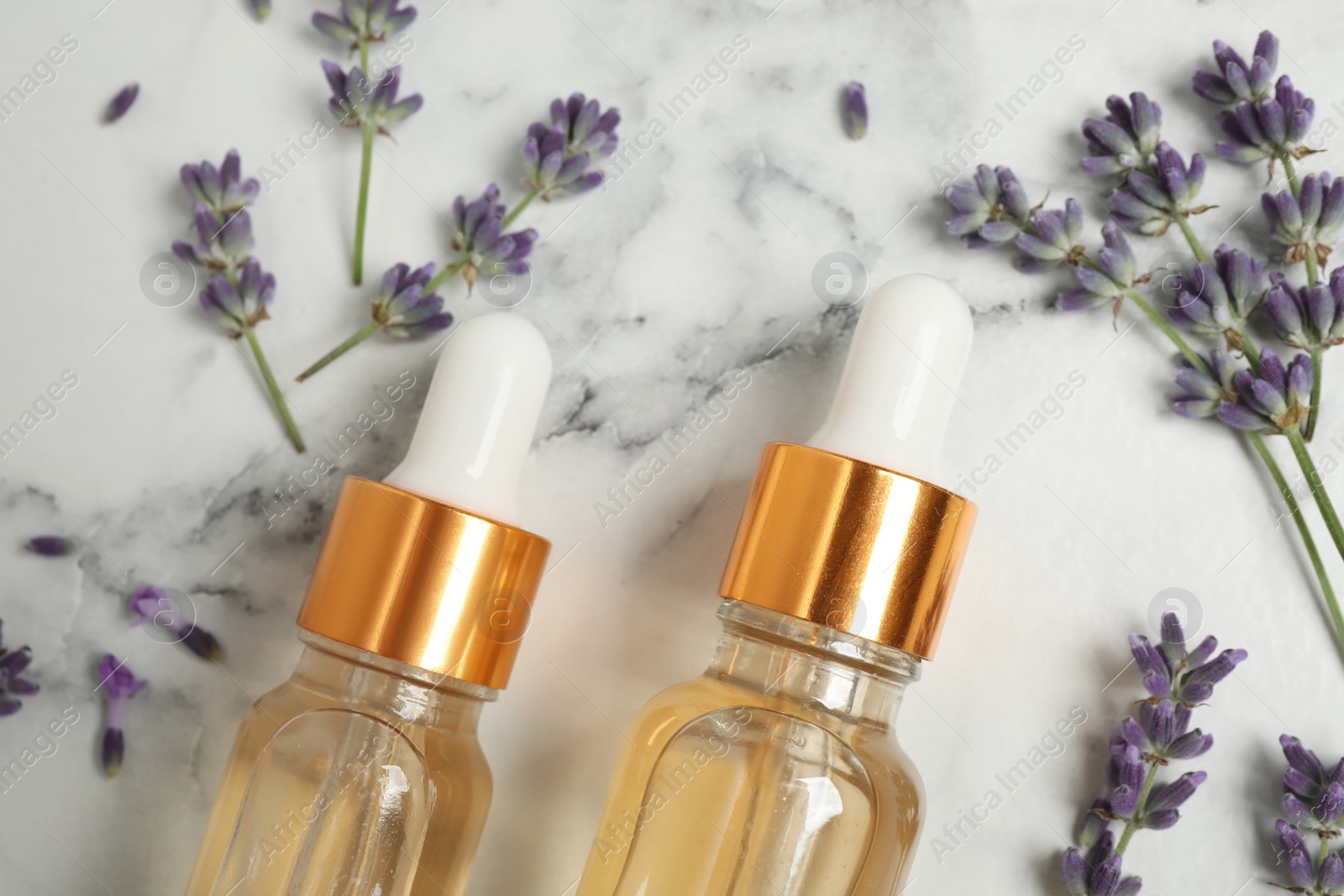 Photo of Flat lay composition with lavender flowers and natural essential oil on white marble table, closeup