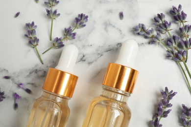 Photo of Flat lay composition with lavender flowers and natural essential oil on white marble table, closeup