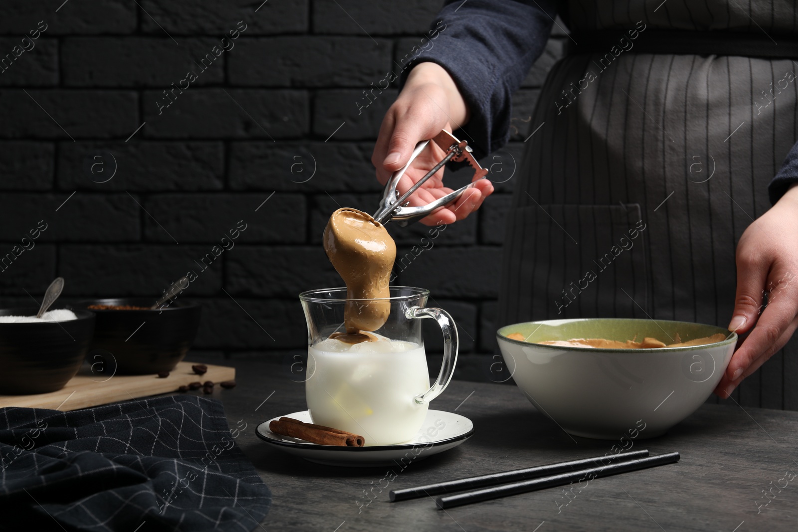 Photo of Woman making dalgona coffee at grey table, closeup