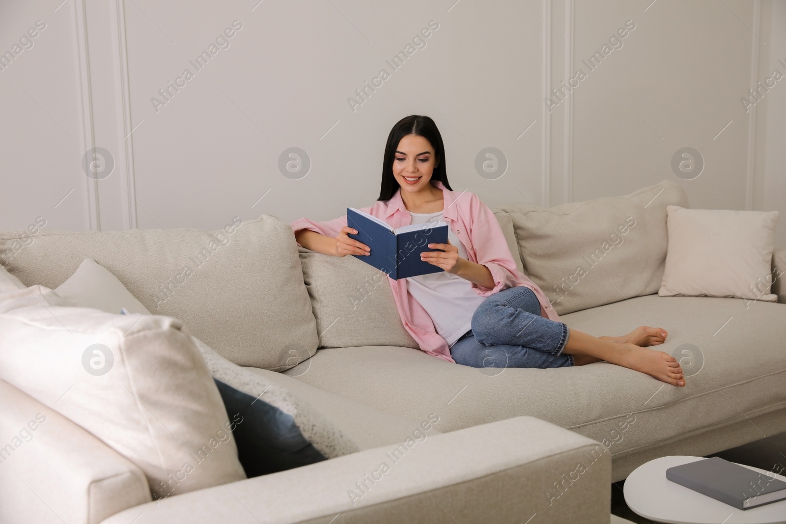 Photo of Woman reading book on sofa in living room