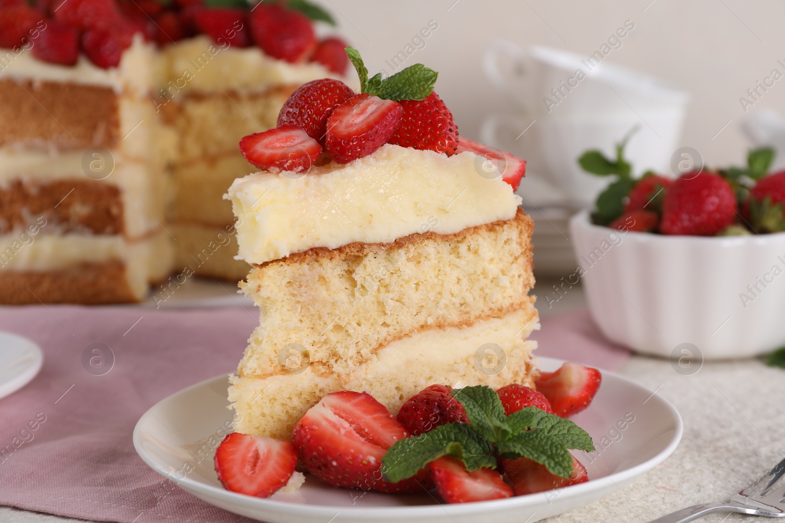 Photo of Piece of tasty cake with fresh strawberries and mint on white table, closeup