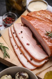 Photo of Delicious smoked bacon with rosemary and peppercorns on wooden board, closeup