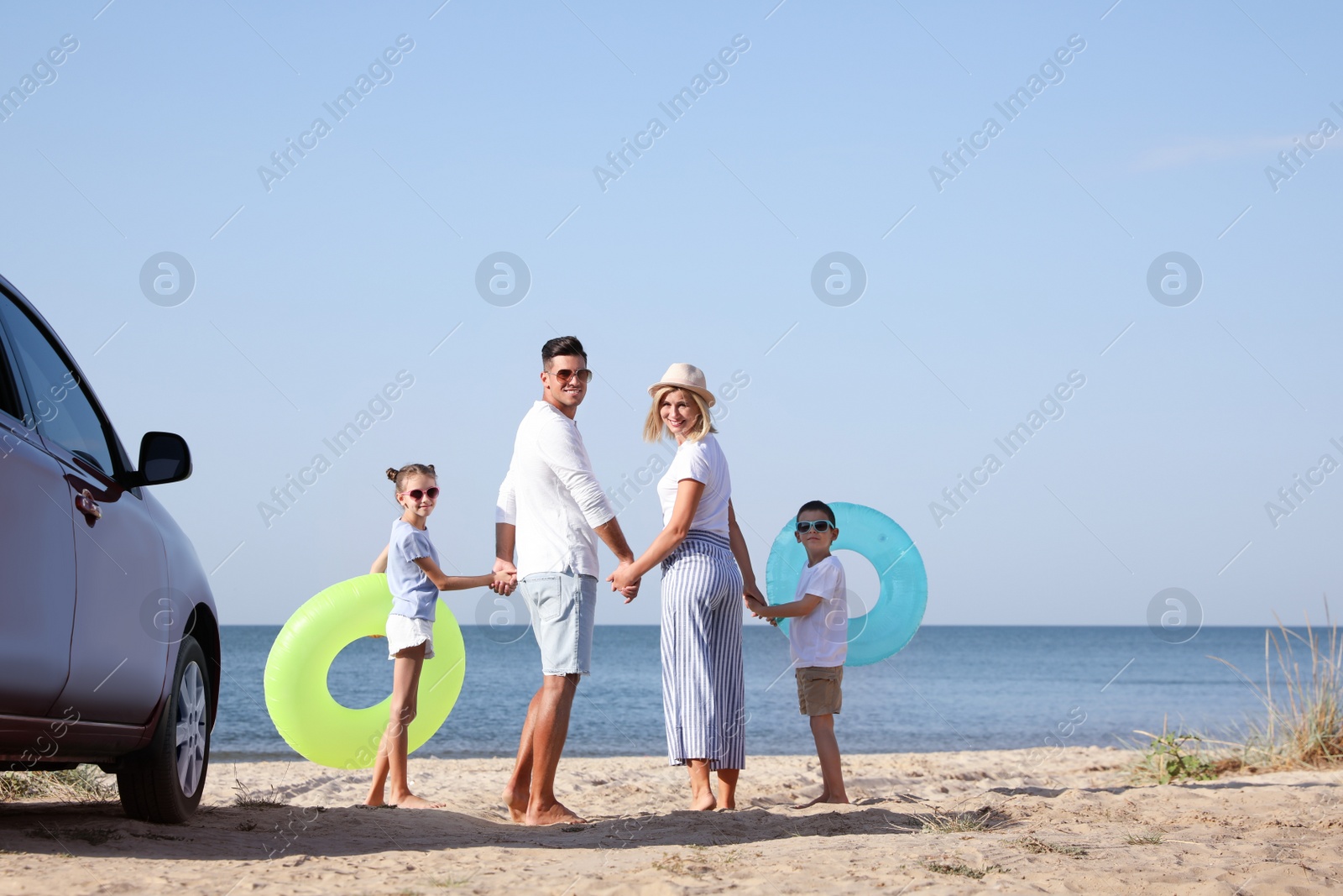 Photo of Family with inflatable rings near car at beach