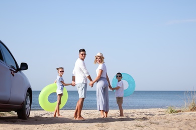 Photo of Family with inflatable rings near car at beach