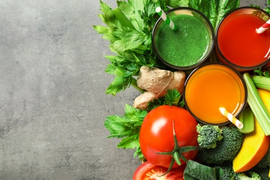 Photo of Delicious vegetable juices and fresh ingredients on grey table, flat lay. Space for text