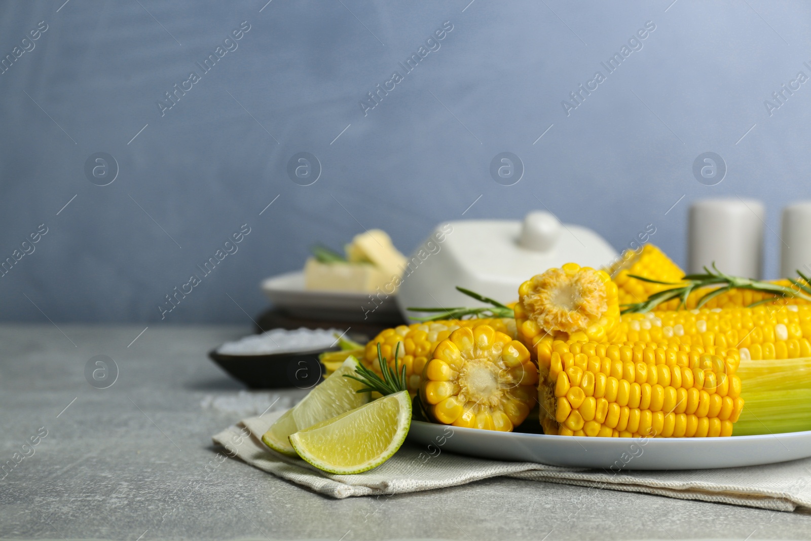 Photo of Tasty boiled corn and ingredients on grey table. Space for text