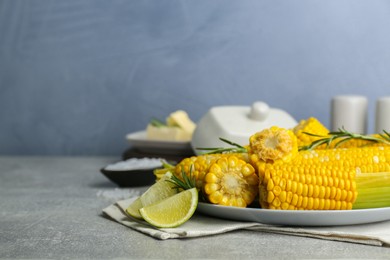 Tasty boiled corn and ingredients on grey table. Space for text