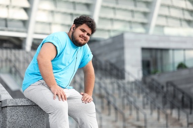 Photo of Young overweight man in sportswear resting outdoors