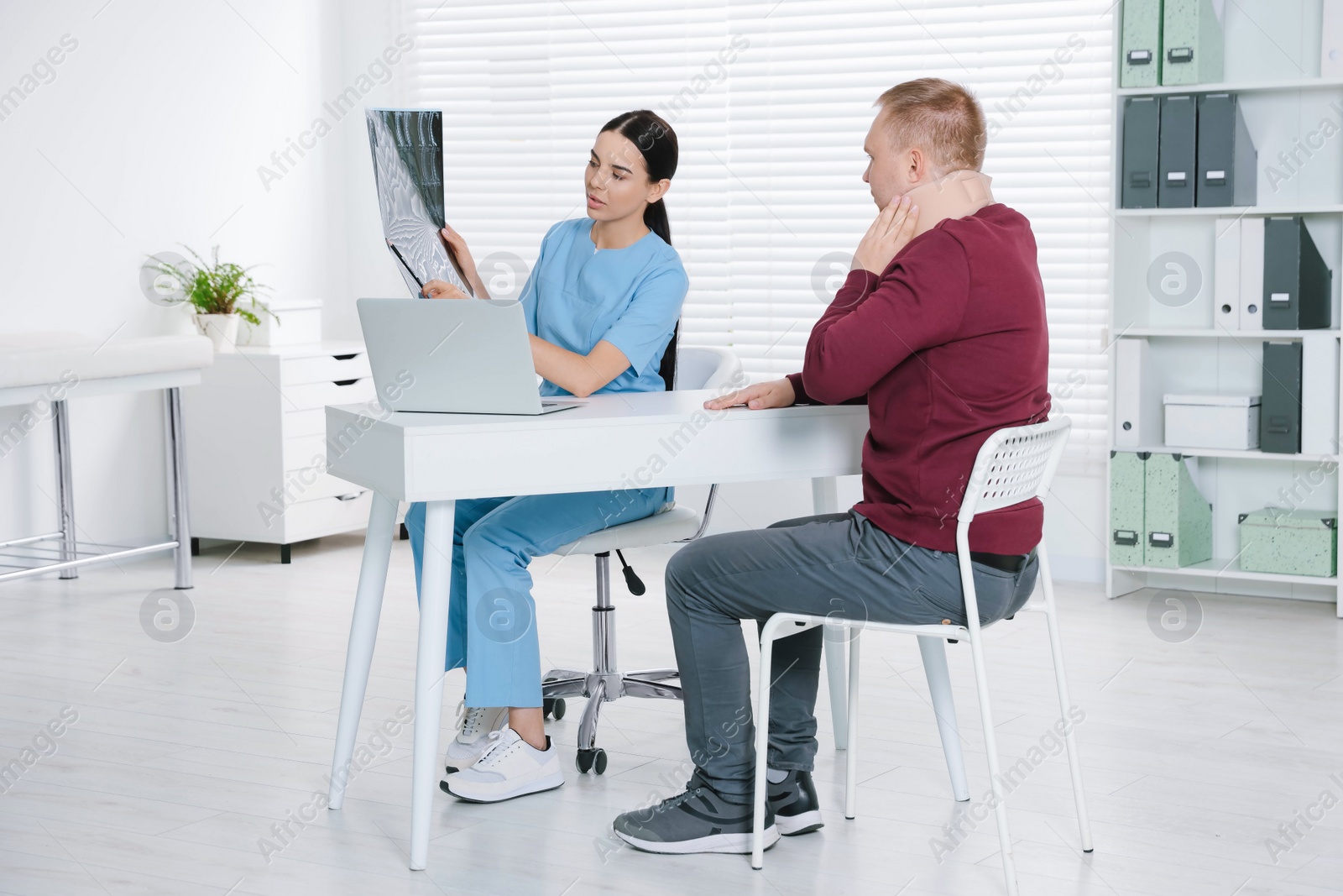 Photo of Doctor with neck MRI image consulting patient in clinic