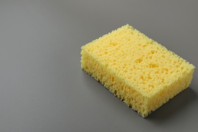 Photo of New yellow sponge on grey background, closeup. Space for text