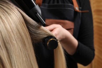 Photo of Hairdresser blow drying client's hair in salon, closeup