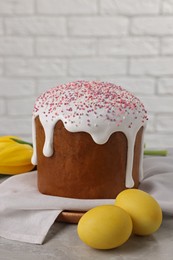 Photo of Tasty Easter cake, decorated eggs and flowers on grey table