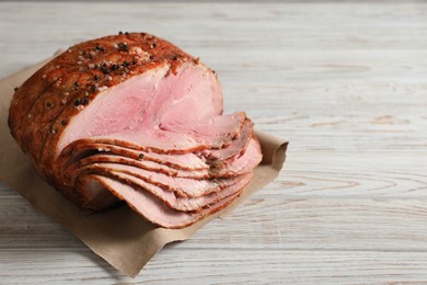 Photo of Delicious sliced baked ham on white wooden table. Space for text