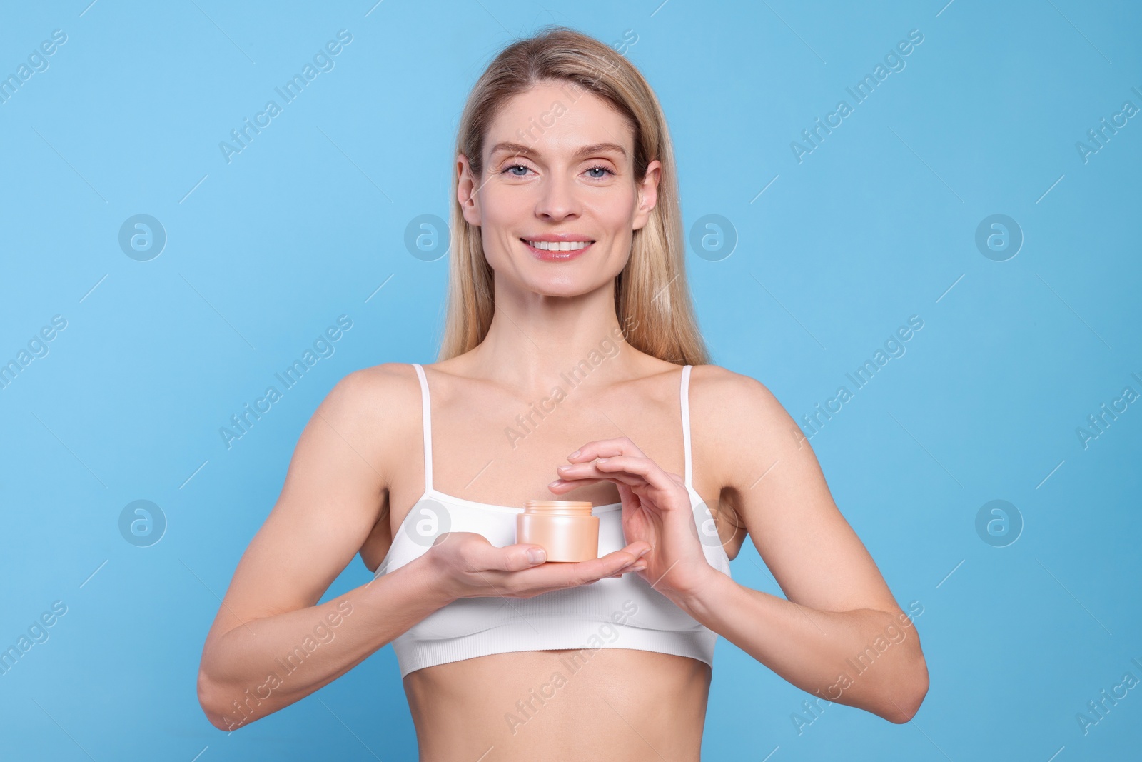 Photo of Woman with jar of body cream on light blue background