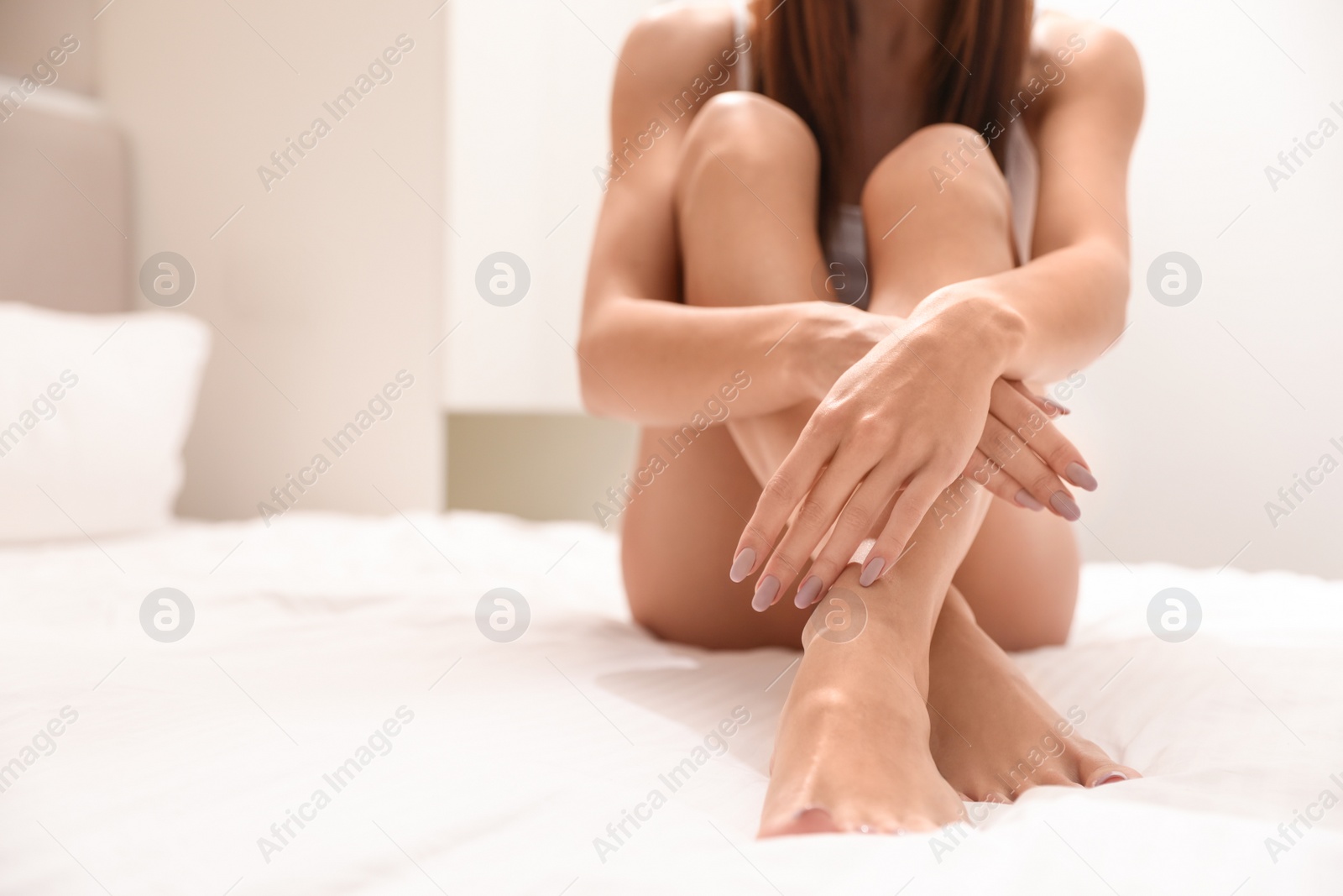Photo of Young woman showing smooth skin after epilation in bedroom, closeup. Space for text