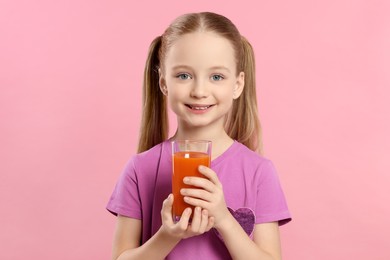 Photo of Cute little girl with glass of fresh juice on pink background