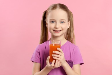 Cute little girl with glass of fresh juice on pink background