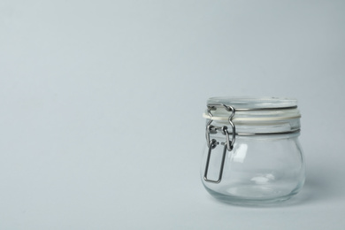 Closed empty glass jar on light background, space for text