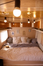 Photo of Stylish room interior with comfortable bed and pillows in modern trailer. Camping vacation
