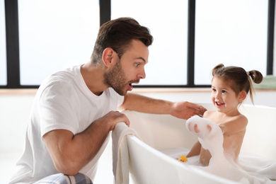 Photo of Young father with cute little daughter in bathroom