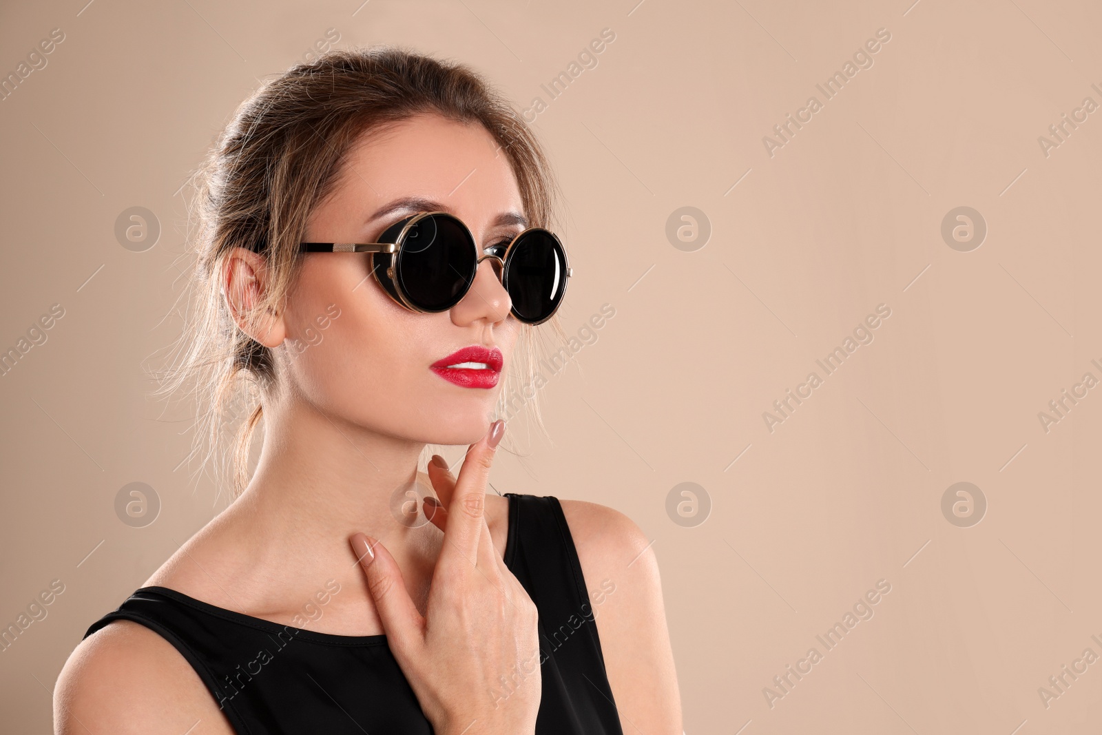 Photo of Young woman wearing stylish sunglasses on beige background. Space for text