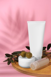 Photo of Cosmetic products and olives on pink background