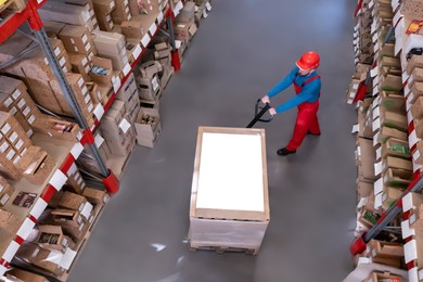 Image of Man in hardhat working with pallet truck at warehouse, above view. Logistics center
