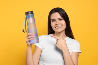 Photo of Young woman with bottle of water on orange background