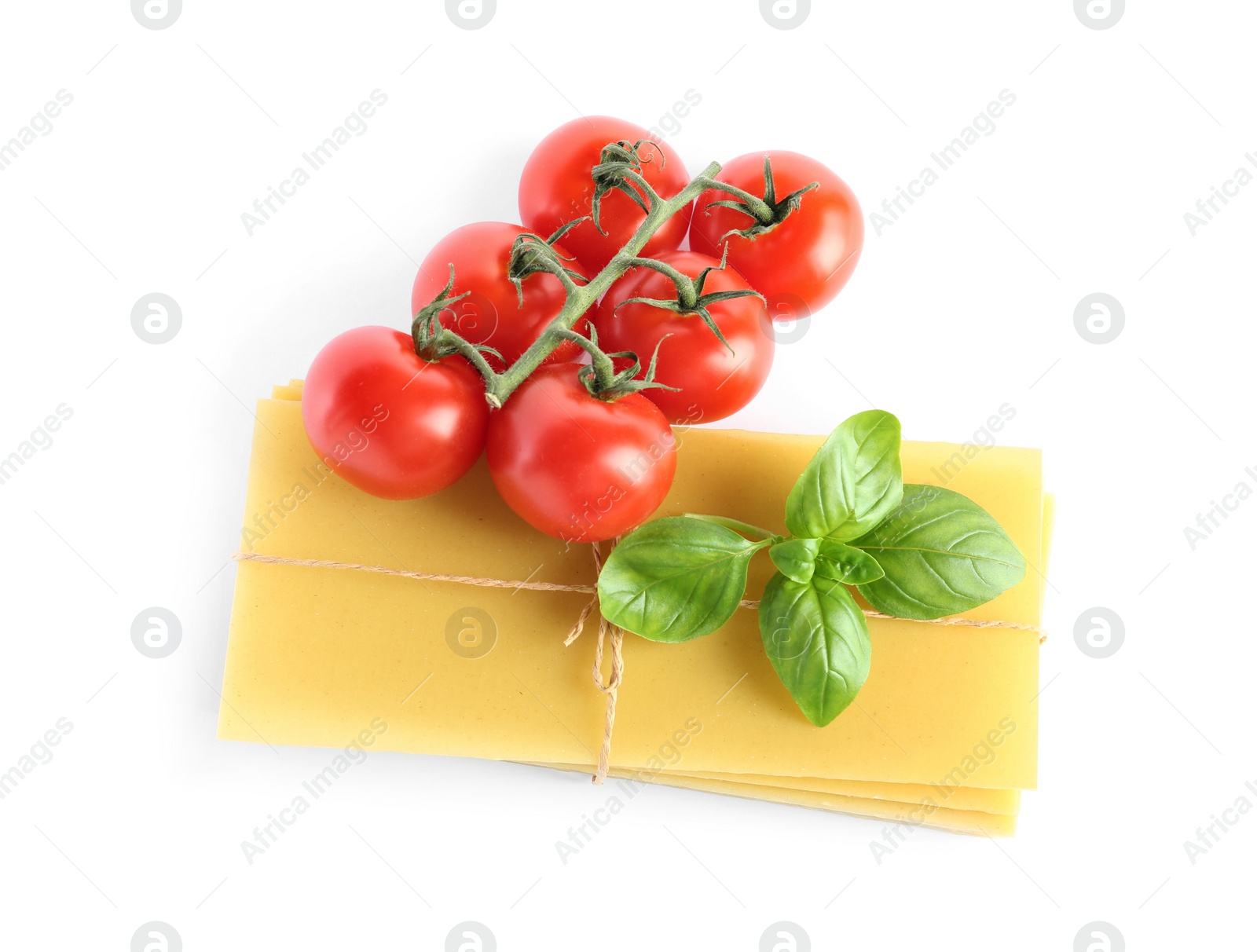 Photo of Uncooked lasagna sheets, tomatoes and basil on white background, top view