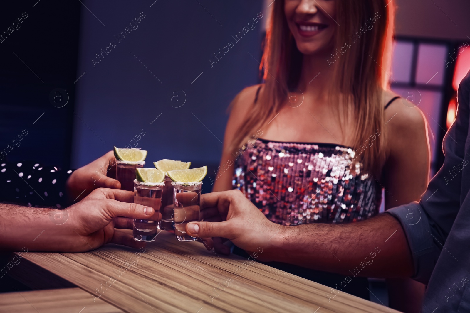 Photo of Young people toasting with Mexican Tequila shots at bar, closeup