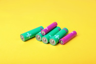 Photo of New AA and AAA batteries on yellow background