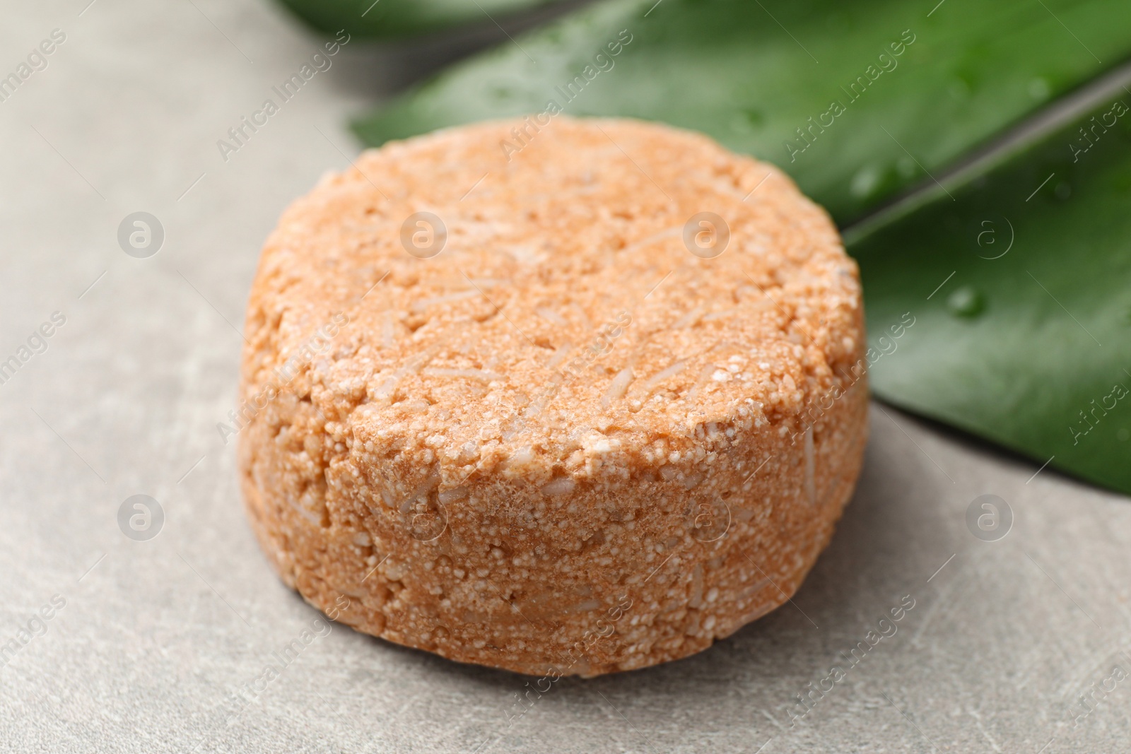 Photo of Natural solid shampoo bar on grey table, closeup