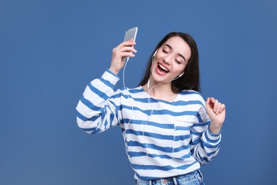 Photo of Young woman using phone for listening to music on color background