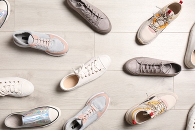 Photo of Flat lay composition with different sneakers on wooden floor