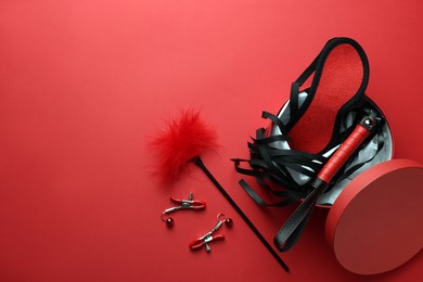 Photo of Gift box with different sex toys on red background, flat lay. Space for text