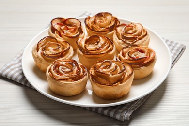 Photo of Freshly baked apple roses on white wooden table. Beautiful dessert