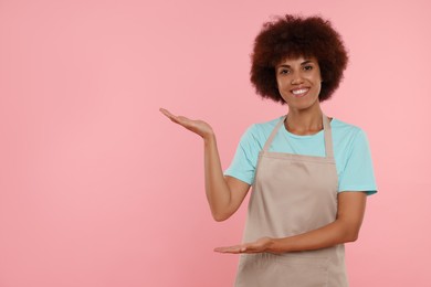 Photo of Portrait of happy young woman in apron on pink background. Space for text