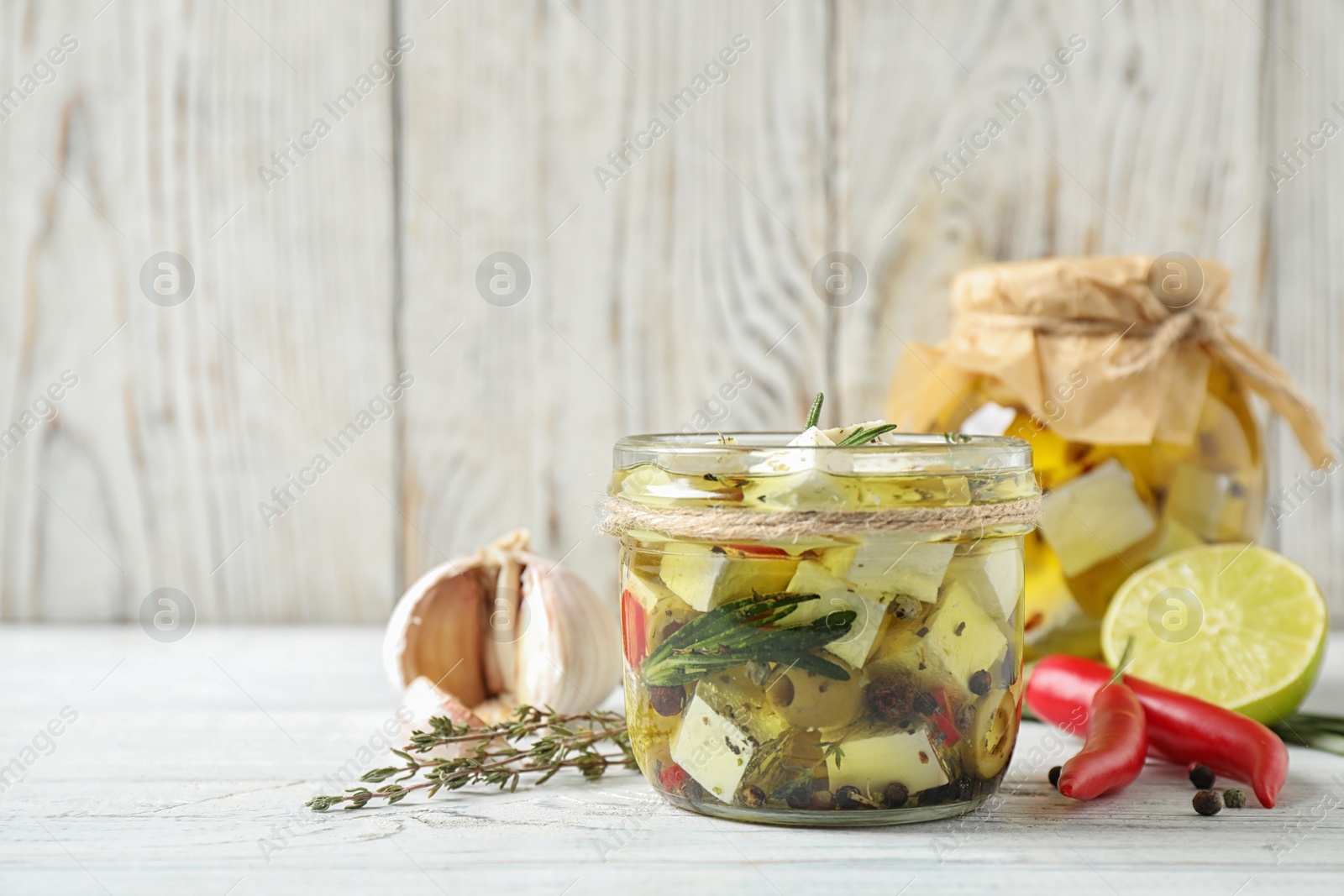 Photo of Composition with pickled feta cheese in jar on white wooden table, space for text