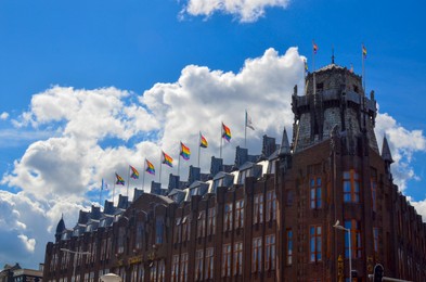 Photo of AMSTERDAM, NETHERLANDS - AUGUST 06, 2022: Bright rainbow LGBT pride flags on building facade