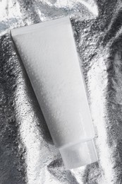 Tube with face cleansing product on silver background, top view