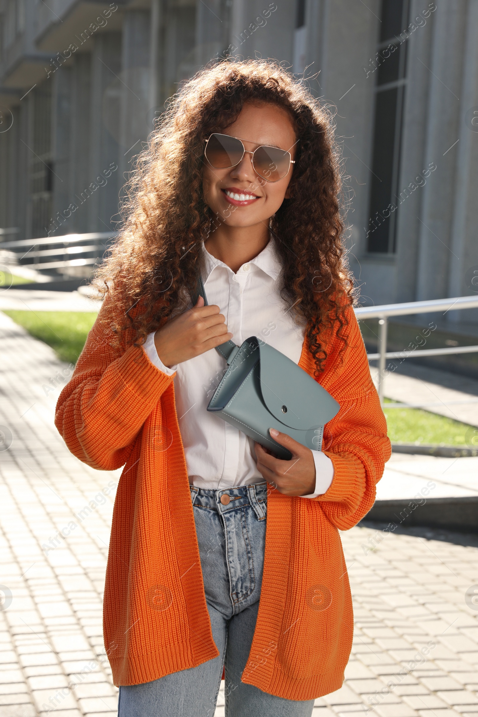 Photo of Beautiful African American woman with stylish waist bag on city street