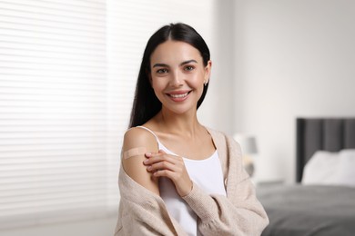 Woman with sticking plaster on arm after vaccination in bedroom