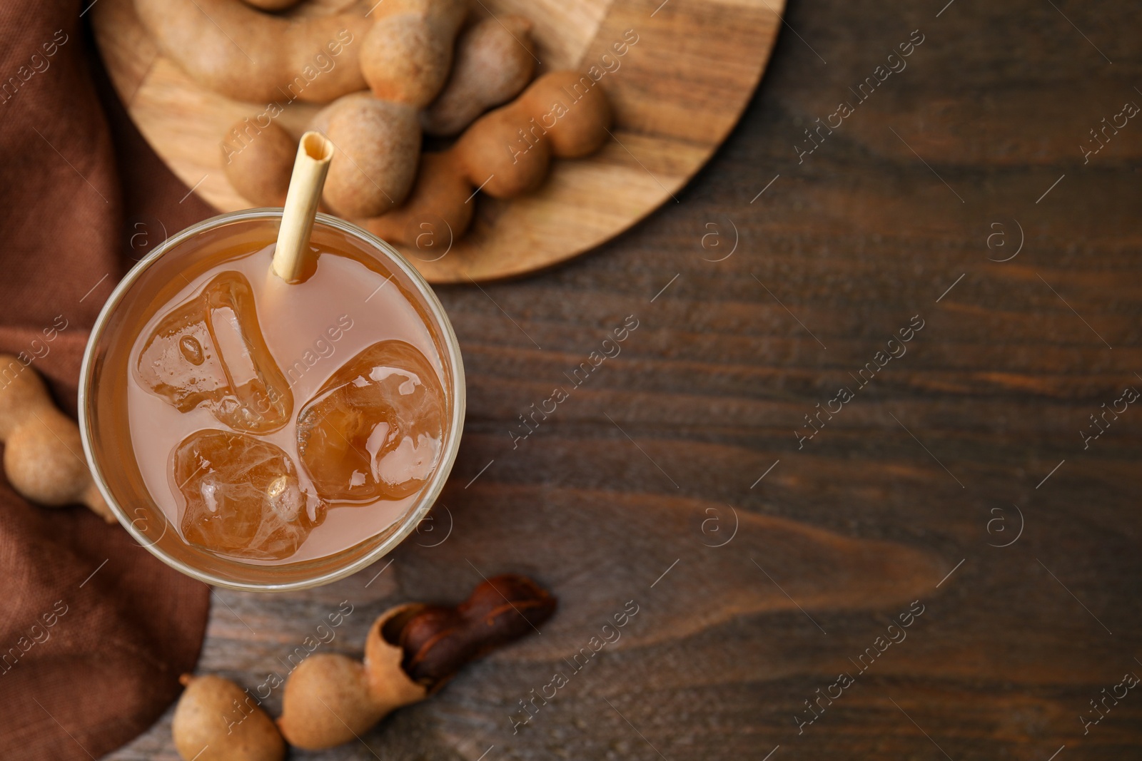 Photo of Tamarind juice and fresh fruits on wooden table, flat lay. Space for text