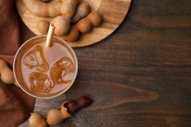 Photo of Tamarind juice and fresh fruits on wooden table, flat lay. Space for text