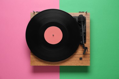 Photo of Modern turntable with vinyl record on color background, top view