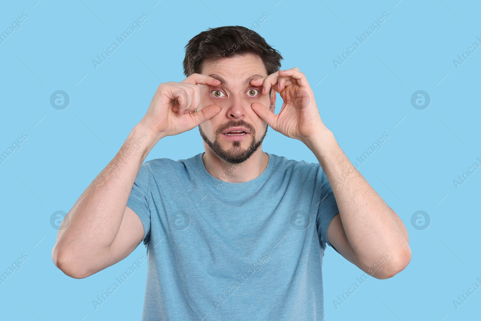 Photo of Tired man on light blue background. Insomnia problem